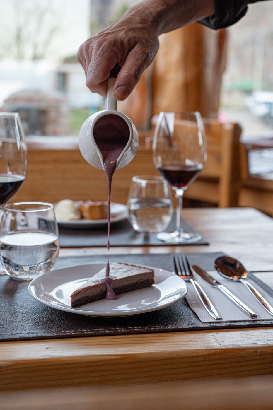Salsa de frutos rojos vertida sobre una porción de némesis de chocolate
