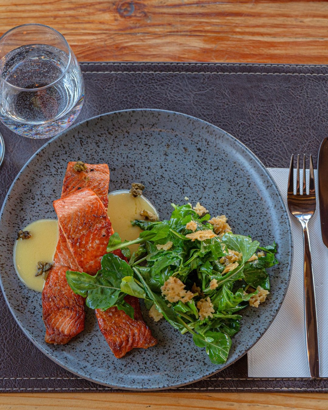 Trucha al hierro con crema y rúcula sobre plato gris
